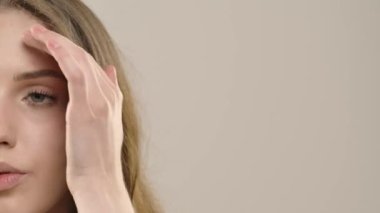 Çekici kadın model kameraya güzellik tedavisi yapıyor. Kameraya poz veren genç bir kadın beyaz arka planda izole edilmiş pürüzsüz tenine dokunuyor. Doğal güzellik cilt bakımı kavramı