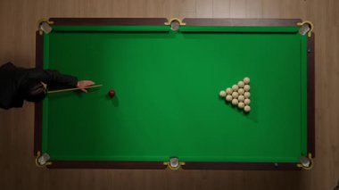 Hobi ve eğlence konsepti. Lüks bilardo kulübü sahnesi. Rus bilardo masasının tam görüntüsü kırmızı topa vurulan beyaz toplar, top piramidine bilardo sopasıyla vuran kişi..