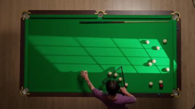 Hobi ve eğlence konsepti. Lüks bilardo kulübü sahnesi. Rus bilardo masasının tam görüntüsü. Beyaz top piramitte düzenleniyor. Topları üçgene yerleştiren kişi.