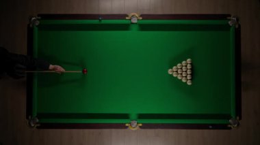 Hobi ve eğlence konsepti. Lüks bilardo kulübü sahnesi. Rus bilardo masasının tam görüntüsü kırmızı topa vurulan beyaz toplar, top piramidine bilardo sopasıyla vuran kişi..