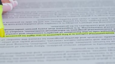 Kadın eli kâğıt üzerinde bir kelimeyi vurguluyor. Kadın elinin belgeyle çalıştığı yakın plan bir fotoğraf, kadın elinde sarı işaret önemli kısımları vurguluyor.