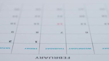 Kadın eli takvim tarihine kırmızı işaretli bir kalp çizer. Kağıt sayfasında ayın 14 'ünde kalp takvimi ile işaretlenmiş kırmızı işaret. Aziz Sevgililer Günü takvimde seçildi.