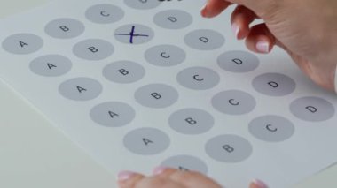 Kağıt üzerinde öğrenci el cevap sınavı. Masadaki kadının önemli bir sınav belgesiyle çalışırken, öğrencinin sınavda okuyup cevap alırken, işaretli harflerle soru işaretleri çizerken yakın plan fotoğrafını çek..