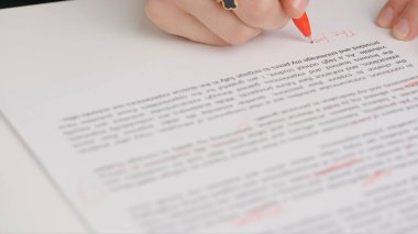 Bayan öğretmen ödevler için not veriyor. Profesyonel okul ya da üniversite öğretmeni öğrencilerin ödev sınav kağıtlarını not eder. Kadın denemeyi kontrol ediyor, yanlış kelimeleri geçiyor, kırmızı kalemle düzeltiyor..