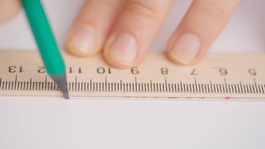 Üniversitede ya da okulda sınava giren kişi. Kadın, geometri sınav kağıdında kalem ve cetvelle doğru cevabı çizer. Cevap kağıdını dolduran öğrenci, yakın çekim..
