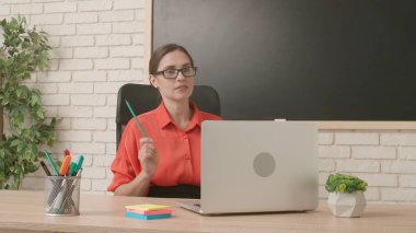 Okulda öğretmen video konferansında. Sınıftaki kadın öğretmen dizüstü bilgisayarla canlı video dersi konferansını canlı yayınlıyor. Uzak bir uzak modern eğitim.