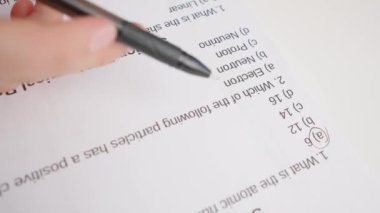 Üniversitede ya da okulda sınava giren kişi. Dişi çemberler, standart sınav kağıdında siyah kalemle doğru cevaplar veriyor. Cevap kağıdını dolduran öğrenci, doğru cevabı seçiyor, yakın çekim.