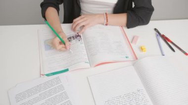 Üniversitede ya da okulda sınava giren kişi. Masadaki kadın, standart sınav kağıdındaki yanlış cevapları kalemle siler. Cevap kağıdını dolduran öğrenci, doğru cevabı seçiyor.