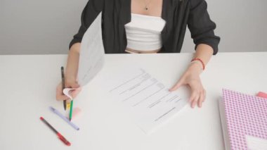 Üniversitede ya da okulda sınava giren kişi. Masadaki stresli kadın standart sınav kağıtlarına bakıyor. Öğrenci sınav için hazırlanıyor, elinde cevapları tutuyor, bunalımda..