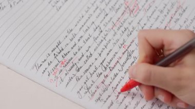 Bayan öğretmen ödevler için not veriyor. Profesyonel okul ya da üniversite öğretmeni öğrencilerin ödev sınav kağıtlarını not eder. Kadın denemeyi kontrol ediyor, yanlış kelimeleri geçiyor, kırmızı kalemle düzeltiyor..
