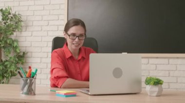 Okulda öğretmen video konferansında. Boş sınıftaki kadın öğretmen dizüstü bilgisayarla canlı video dersi konferansını canlı yayınlıyor. Uzak bir uzak modern eğitim.