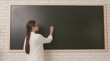 Okul öğretmeni sınıfta gençlerle konuşuyor. Kadın üniversite öğretmeni sınıfın önünde duruyor ve öğrencilere matematik dersi veriyor. Eğitim kavramı.