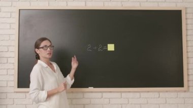 Okul öğretmeni sınıfta gençlerle konuşuyor. Kadın üniversite öğretmeni sınıfın önünde duruyor ve öğrencilere ders veriyor. Üzerinde yapışkan notlar vardı. Eğitim kavramı.