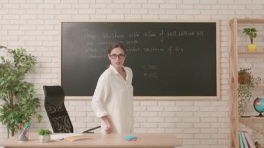 Okul öğretmeni sınıfta gençlerle konuşuyor. Kadın üniversite öğretmeni sınıfın önünde duruyor ve öğrencilere fizik dersi veriyor. Eğitim kavramı.