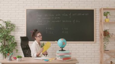 Sınıfta öğretmen çalışma günü. Komik saç stili olan karizmatik bir üniversite öğretmeni sınıfta oturmuş elinde bitki ve el sallayan bir fanla esrar tutuyor. Eğitim kavramı.