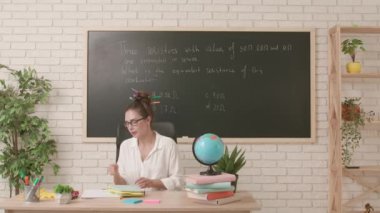 Sınıfta öğretmen çalışma günü. Komik saç stili olan karizmatik kadın üniversite öğretmeni sınıfta oturuyor, duygusal olarak dersini anlatıyor, elinde yapışkan notlarla kitap tutuyor. Eğitim kavramı.