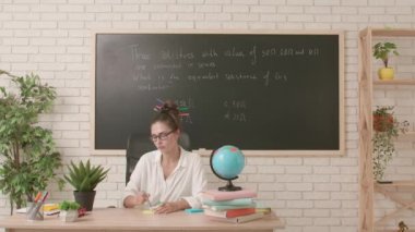 Sınıfta öğretmen çalışma günü. Komik saç stili olan karizmatik bir üniversite öğretmeni sınıfta oturmuş yapışkan nota yıldız çiziyor ve alnına yapıştırıyor. Eğitim kavramı.