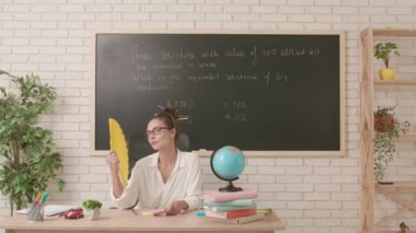 Sınıfta öğretmen çalışma günü. Komik saç stili olan karizmatik bir üniversite öğretmeni sınıfta oturuyor. Yapışkan nota kalp çiziyor ve tişörte takıyor. Eğitim kavramı.