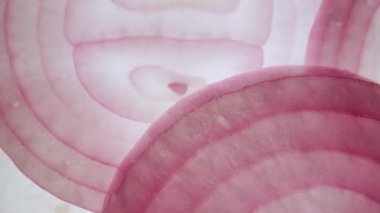 Sebze rengi desenli arka plan. Çatı penceresine doğru hareket eden taze, sulu mor soğan dilimlerinin makro çekimi, ışık altında görülebilen sulak yapılı et ve daireleri gösteriyor..