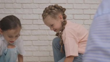 Anaokulu derslerini ziyaret eden bir grup çocuk. Genç öğretmen ve bir grup çocuk yerde oturuyor ve geliştirme derslerinde oyuncakçılık ve inşaatçılık oynuyorlar. Çocuk eğitimi konsepti. Yavaş çekim.