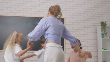Anaokulu derslerini ziyaret eden bir grup çocuk. Gelişim sınıfındaki bir grup çocuk el ele tutuşup daireler çizerek eğleniyorlar. Çocuk eğitimi konsepti. Yavaş