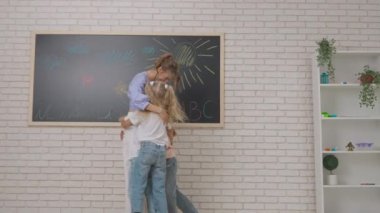 Anaokulu derslerini ziyaret eden bir grup çocuk. Gelişim sınıfındaki genç öğretmenler ve bir grup çocuk, çocuklar birlikte bayan öğretmenlere sarılıyor, herkes gülümsüyor. Çocuk eğitimi konsepti. Yavaş çekim.