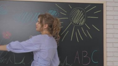 Anaokulu derslerini ziyaret eden bir grup çocuk. Gelişim sınıfındaki bir grup genç öğretmen, çocuklar ve öğretmenler el sallıyor ve kızlar kaçıyor. Çocuk eğitimi konsepti. Yavaş çekim.