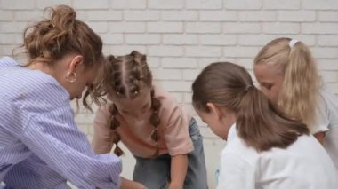 Anaokulu derslerini ziyaret eden bir grup çocuk. Genç bayan öğretmen ve bir grup çocuk yerde oturuyor ve gelişim derslerinde yaratıcı işler yapıyorlar. Çocuk eğitimi konsepti.