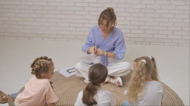 Anaokulu derslerini ziyaret eden bir grup çocuk. Genç bayan öğretmen ve bir grup çocuk gelişim derslerinde yaratıcı görevler yapıyor, alfabe öğreniyorlar. Çocuk eğitimi konsepti.