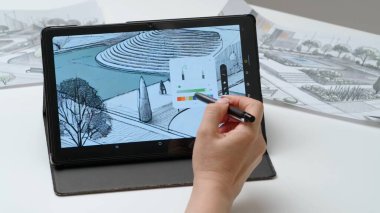 Tablet ve kalem kullanan kadın tasarımcı çizer. Kadın mimar tasarımcı, şehir parkının el boyama projesi Stylus ile birlikte grafik tablet sergisinde çalışıyor. Yaratıcılık ve modern teknoloji.