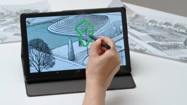 Tablet ve kalem kullanan kadın tasarımcı çizer. Kadın mimar tasarımcı, şehir parkının el boyama projesi Stylus ile birlikte grafik tablet sergisinde çalışıyor. Yaratıcılık ve modern teknoloji.