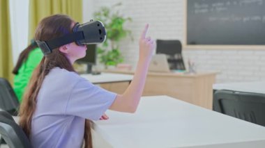 Sanal gerçeklik kulaklığı takan bir öğrenci, dijital elementlere işaret ederek ve etkileşimde bulunarak, bir sınıfta etkileşimli bir sanal gerçeklik oturumuna katılır. Kapsamlı teknoloji ile öğreniyorum..