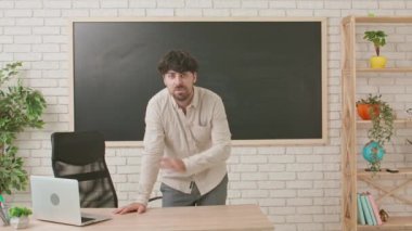 Bir erkek öğretmen tebeşir tahtasının önünde öğrencilere bir dersi açıklıyor. Erkek öğretmen duygusal olarak hareket ediyor ve sinirleniyor. Eğitim anlayışı, bir okulda veya üniversitede öğretmenlik.