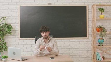 Sınıfta arka planda tahtayla oturan, portatif kulaklık takan ve müzikten hoşlanan erkek öğretmen. Eğitim kavramı, okulda veya üniversitede öğretmenlik.