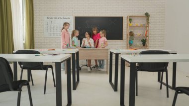 Bir grup ilkokul öğrencisi fen bilgisi öğreniyor. Ortaokul öğrencileri fen kimyası dersinde sınıfta otururlar. Bayan öğretmen kimyasal deney gösteriyor, çocuklar dersten zevk alıyor. Modern eğitim.