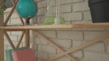 Bir grup ilkokul öğrencisi fen bilgisi öğreniyor. Ortaokul fen dersi kimya dersi çekimi. Salondaki rafları bilim kitapları ve cam test tüpleriyle kapatın. Yavaş çekim.