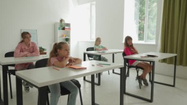 Bir grup ilkokul öğrencisi fen bilgisi öğreniyor. Ortaokul öğrencileri fen bilimleri kimyası dersinde. Öğretmen çocuklarla konuşur, dersi açıklar, çocukları dinler. Yavaş çekim.