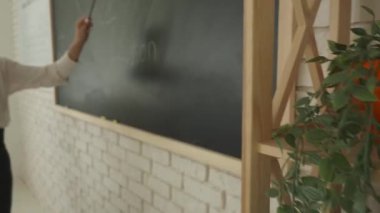 Bir grup ilkokul öğrencisi fen bilgisi öğreniyor. Ortaokul öğrencileri fen bilimleri kimyası dersinde. Öğretmen karatahtadaki formülü çocuklara, dinleyen çocuklara açıklıyor. Yavaş çekim.