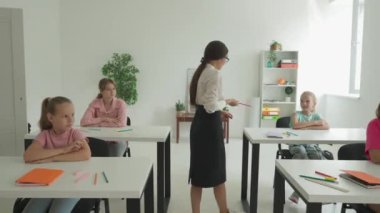 Bir grup ilkokul öğrencisi fen bilgisi öğreniyor. Ortaokul öğrencileri fen kimyası dersinde sınıfta otururlar. Bayan öğretmen sınıfta yürüyor ve çocuklara sorular soruyor. Modern eğitim kavramı.