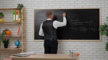 Okul öğretmeni sınıfta gençlerle konuşuyor. Erkek üniversite öğretmeni sınıfın önünde öğrencilere kimya dersi veriyor, formüller yazıyor. Eğitim kavramı.