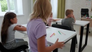 Bir grup ilkokul öğrencisi. Sınıftaki ortaokul öğrencileri, kadın öğretmenler çocuklara ders veriyor, çocuklar ödevlerini bitirip özel öğretmene veriyorlar. İlkokul.