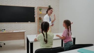 Bir grup ilkokul öğrencisi. Sınıftaki ortaokul öğrencileri, kadın öğretmen çocuklara ders veriyor, çocuklarla dost canlısı özel hocalar beşlik çakıyor. İlkokul.