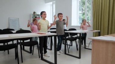 Bir grup ilkokul öğrencisi. Sınıftaki ortaokul öğrencileri, kadın öğretmen ve çocuklar ders sırasında ısınma egzersizleri yapıyorlar. İlkokul.