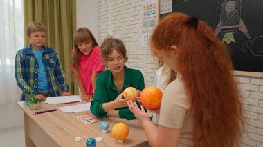Bir grup ilkokul öğrencisi sınıfta fen bilgisi öğreniyor. Ortaokul öğrencileri ve kızlar astronomi sınıfında oturuyor. Bayan öğretmen gezegen modelini elinde tutuyor ve bunu çocuklara açıklıyor. Modern eğitim kavramı