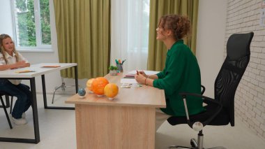 Bir grup ilkokul öğrencisi sınıfta fen bilgisi öğreniyor. Astronomi sınıfındaki orta okul öğrencileri ve kızlar. Kadın öğretmen güneş sistemiyle konuşuyor, dünya kartını gösteriyor. Modern eğitim kavramı.