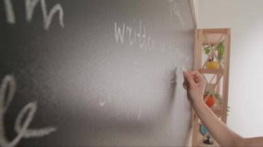 Bayan öğretmenin elinde tebeşir var. Karatahtaya kadın el yazısı metni ve formüllerini kapatın. Profesör tahtaya ya da öğrenci çözme görevine yazıyor. Eğitim ve bilim konsepti.