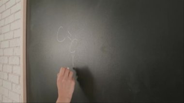 Bayan öğretmenin elinde tebeşir var. Karatahtaya kadın el yazısı formülleri yazmaya yakın bir yerde profesör tahtaya ya da öğrenci çözme görevine yazı yazıyor. Eğitim ve bilim konsepti.