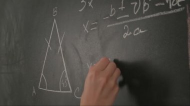 Bayan öğretmenin elinde tebeşir var. Karatahtaya kadın el yazısı ve trigonometri formüllerini kapatın, profesör tahtaya ya da öğrenci çözme görevine yazıyor. Eğitim ve bilim konsepti.