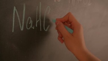 Bayan öğretmenin elinde tebeşir var. Karatahtaya kadın el yazısı formülleri yazmaya yakın bir yerde profesör tahtaya ya da öğrenci çözme görevine yazı yazıyor. Eğitim ve bilim konsepti.