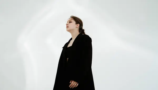 stock image Young woman in black clothes dancing contemporary on white background.